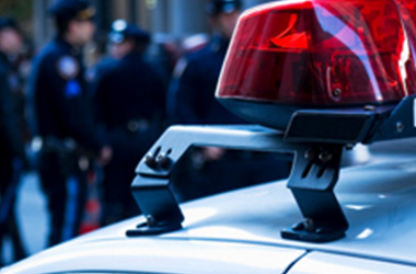 Close up of light on top of police car with police men and women in background